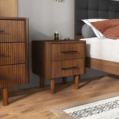 Wooden nightstand with two drawers next to a bed with a gray headboard.