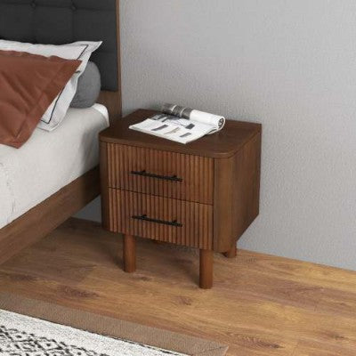 Wooden nightstand with two drawers next to a bed with a gray headboard.