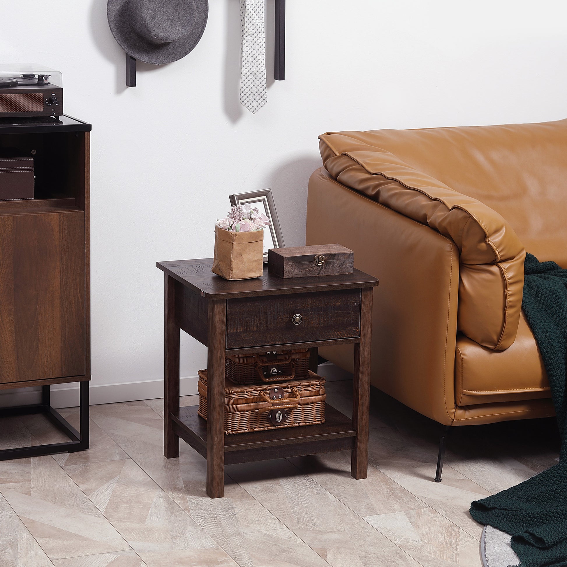 Wooden side table with decorative items next to a brown leather sofa in a living room.