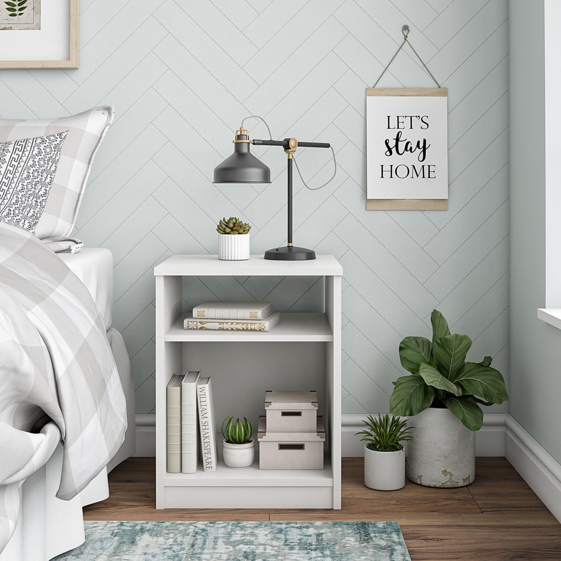 White nightstand with books, plants, and a lamp in a bedroom setting.