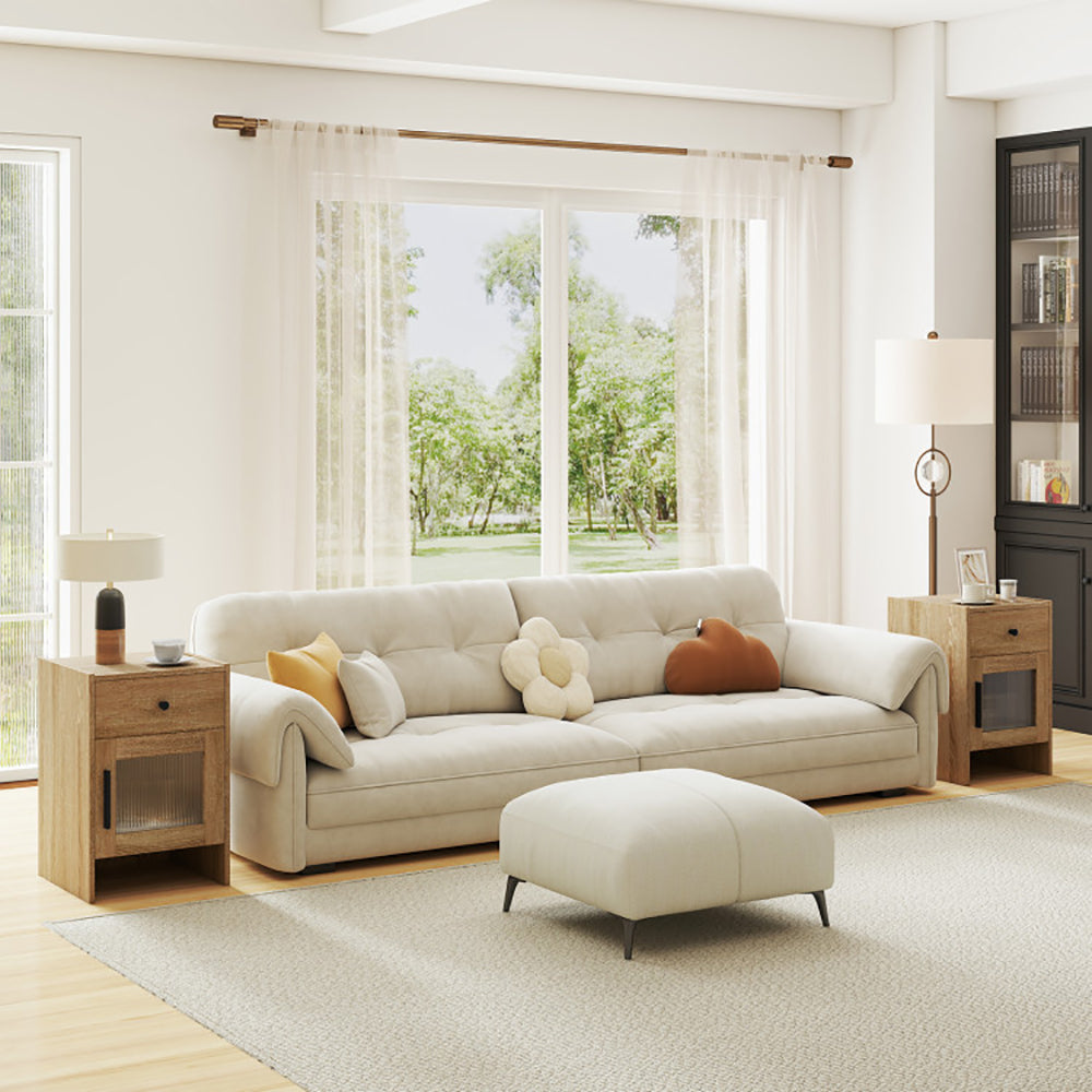 Modern living room with a beige sectional sofa, ottoman, and side tables.