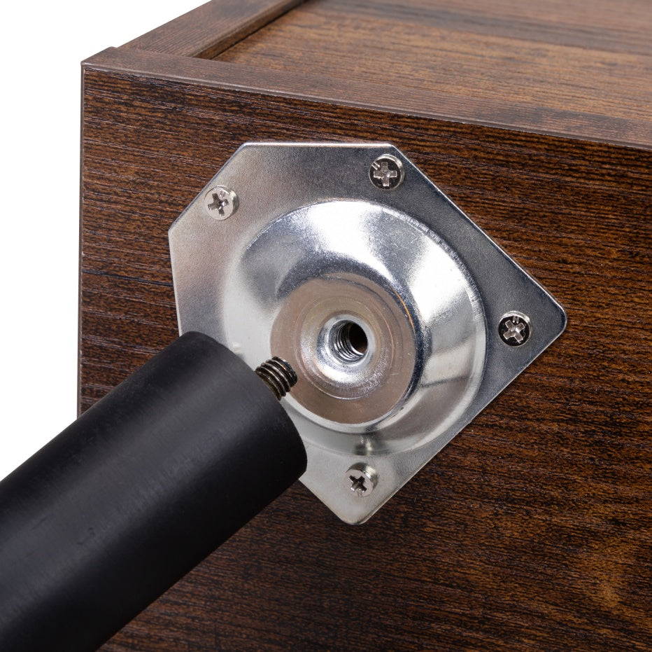 Metal bracket on a wooden surface with a black cylindrical object interacting with it.