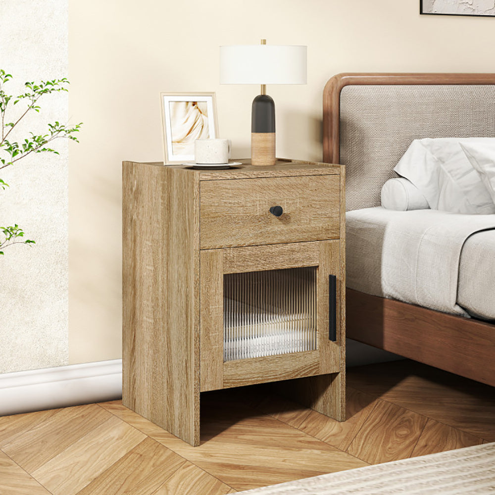 Wooden nightstand with a lamp and decor item next to a bed in a bedroom setting.